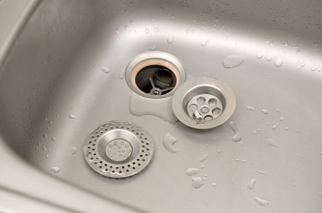 Silvery kitchen sink with a disassembled protective filter. Kitchen sink repair process